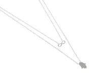 Collar doble de plata 925 con cadena de eslabones. El collar superior presenta un dije de infinito y el collar inferior presenta un dije de hamsa.