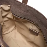 Cartera tipo tote compacta y estructurada, color marrón, con material exterior de símil gamuza combinado con PU liso. Cuenta con doble asa corta rígida, correa larga regulable y desmontable, y herrajes metálicos dorados. El compartimento principal tiene cierre superior y un bolsillo interno con cierre.