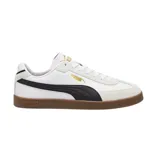 Championes Puma modelo Club Li Era, de diseño urbano con base blanca, franja lateral negra y suela de goma color caramelo. Presenta detalles en gamuza gris en la puntera y talón, con logo de la marca en dorado.