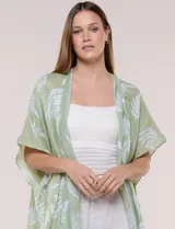 Kimono de gasa verde con estampado de hojas blancas y detalles de lurex. Presenta mangas cortas holgadas, diseño abierto al frente y terminación en punta con borlas en el ruedo.
