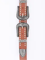 Cinto de cuero sintético color marrón con doble hebilla metálica plateada de estilo western con grabados florales y detalles de tachas metálicas.