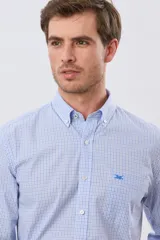 Camisa de manga larga con estampado de cuadros pequeños en tonos celeste y blanco, cuello abotonado, bolsillo en el pecho con detalle bordado y cierre frontal de botones.
