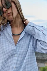 Camisa de manga larga con cuello solapa y cierre frontal de botones, confeccionada en tejido de algodón con estampado de cuadros vichy en tonos azul y blanco.