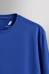 Camiseta deportiva de manga larga Zara Athleticz, de corte regular fit y color marrón topo. Confeccionada en tejido técnico elástico de secado rápido, cuenta con cuello redondo y detalle de logo estampado en el bajo.