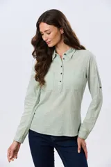 Camisa de lino lisa color celeste, de manga larga con puños abotonados y trabilla para arremangar. Cuenta con cuello clásico, cierre frontal con botones y bolsillos plaqué en el pecho.