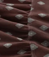 Falda midi de tul con estampado de corbatas, cintura elástica y diseño con volados. Presenta un forro más corto que crea un efecto de transparencia en el ruedo.