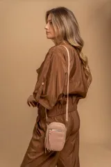 Bandolera compacta color rosado, con correa regulable y desmontable. Tiene apertura superior, bolsillo frontal con cierre y detalle de borla, y bolsillo trasero sin cierre. El interior está forrado en tela y cuenta con un bolsillo adicional.