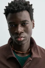 Polo de hombre de corte relajado, color marrón oscuro, confeccionado en tejido texturizado con rayas verticales. Posee cuello solapa y cierre frontal con botonadura oculta por solapa.