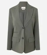 Blazer de sastrería color verde oliva, con corte oversized, solapas clásicas, cierre frontal de un botón y bolsillos con tapa. Cuenta con forro interno y textura sutil.