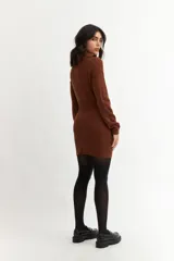 Vestido corto negro de tejido de punto acanalado, con mangas largas y medio cierre frontal.