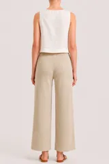 Pantalón de punto color beige, de corte recto y holgado. Presenta cintura elástica con cordón de ajuste y costuras verticales decorativas en el frente.