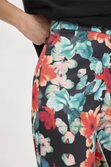 Pantalón palazzo de tela fluida con estampado floral en tonos naranja, celeste y blanco sobre fondo negro.