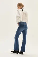 Jean de mezclilla azul de tiro medio, con silueta ligeramente acampanada desde la rodilla.