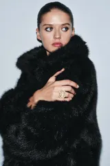 Anillo de metal dorado con banda texturizada y chatón rectangular incrustado con múltiples piedras negras.