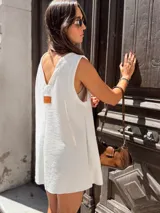 Vestido corto blanco tipo jumper, confeccionado en tejido escocés con textura. Presenta escote en V y bolsillos delanteros.