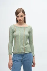 Remera de manga larga en color verde melange, con cuello bote y costuras decorativas verticales en contraste de colores.