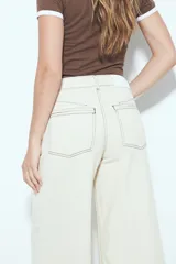 Pantalón de pierna amplia color beige, con silueta relajada y calce cómodo, confeccionado en denim con leve elasticidad. Presenta costuras a contraste.
