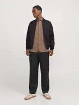 Campera bomber negra de tejido liviano de lino y algodón, con cuello tipo baseball, cierre con cremallera, mangas largas con puños de canalé y bolsillos delanteros.