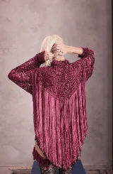 Camisa de encaje color bordó con cuello clásico y mangas largas. Presenta un diseño con flecos largos de seda que recorren la parte trasera y delantera, aportando movimiento y textura a la prenda.