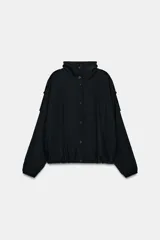 Chaqueta oversize de modal con cuello subido, cierre frontal con botones a presión y mangas largas con puños elásticos. Presenta trabillas en los hombros, bolsillos de vivo en el delantero y bajo abullonado con elástico.