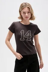 Remera de algodón color marrón oscuro, de manga corta y corte ajustado al cuerpo, con cuello redondo a la base y detalle de bordado con tachas formando el número 14 en el frente.