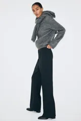 Pantalón en punto pesado de tiro alto, color negro, con elástico oculto en la cintura, cierre y pretina prolongada con corchete oculto. Piernas bootcut con raya cosida.