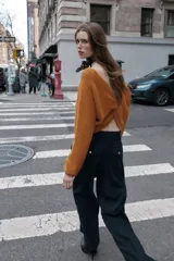 Pantalón de tiro alto color bordó, con pinzas delanteras, bolsillos frontales y falsos bolsillos con solapa en la espalda. Tiene pernera ancha y cierre frontal con cremallera, botón interior y gancho.