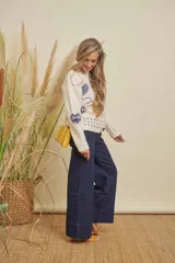 Buzo de punto color crema con estampado de corazones en tonos azul, rojo y amarillo, y detalles cuadrados en gris en el ruedo. Tiene cuello redondo y mangas largas.