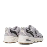 Championes New Balance 530 de estilo urbano, confeccionados en malla gris y superposiciones de gamuza en tono lila. Cuentan con detalles en negro, entresuela blanca ABZORB y suela de goma con tacos marrones.