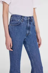 Jean de denim azul oscuro, de tiro alto y corte flare con pernera ancha acampanada.