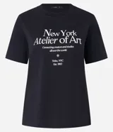 Remera negra de algodón con cuello redondo y mangas cortas. Estampa frontal con texto "New York Atelier of Art".