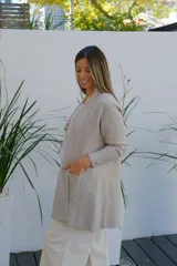 Saco tipo cárdigan abierto de corte recto y largo medio, color visón, con mangas largas y bolsillos frontales aplicados.