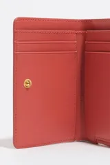 Billetera pequeña de estructura rígida, color negro, con estampado frontal en color dorado con la palabra "BIMBA". Posee cierre superior con tirador de tela amarillo mostaza.