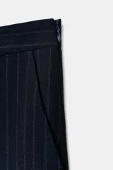 Pantalón de tiro alto con pinzas frontales, diseño de raya diplomática, bolsillos laterales y bajo con vuelta.