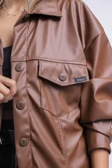 Camisa marrón de cuero sintético, con cuello clásico, cierre frontal con botones a presión y bolsillos con solapa en el pecho.