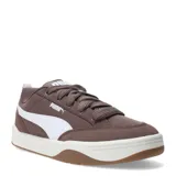 Championes Puma de estilo urbano inspirados en el skate, con perfil bajo. Presentan una estructura combinada de material sintético y superposiciones de gamuza en color negro, con el icónico logo de la marca en blanco en el lateral. Cuentan con cordones gruesos en color crema, entresuela blanca y suela de goma color caramelo.