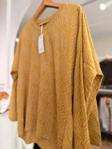 Buzo de tejido de punto con diseño de estampado tipo cebra y sutiles hilos dorados integrados. Presenta cuello redondo, mangas largas y un corte holgado.