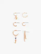 Set de seis aros de diferentes estilos en tono dorado, incluyendo aros tipo argolla, aros con dije de corazón, aros con dijes de cristales de colores y aros con tiras de strass colgantes.
