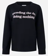 Blusa de pijama negra de algodón con cuello redondo, mangas largas y estampa frontal con la frase "spending the day doing nothing".