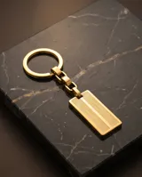 Llavero de acero con baño en oro, compuesto por un aro, una cadena de eslabones y una placa rectangular con textura grabada.