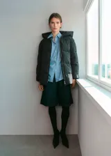 Campera puffer negra con capucha, cuello alto y cierre frontal de cremallera doble. Diseño acolchado de manga larga con acabado repelente al agua.