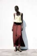 Top corto color crema confeccionado con lino, escote pico y tirantes finos. Detalle de espalda abierta con tira elástica horizontal y bajo abullonado con elástico interior.