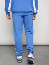 Pantalón deportivo azul claro con puños ajustados en los tobillos. Presenta el escudo del Club Nacional de Football bordado en la pierna izquierda y el logo de Umbro bordado en la derecha.