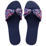 Sandalias Havaianas modelo You St Tropez de color azul marino, con tira frontal de tela estampada con diseño floral en tonos rosas y blancos, anudada en el centro.