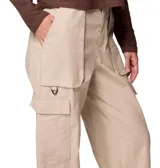 Pantalón cargo de corte holgado en color beige, con cintura de tiro medio, múltiples bolsillos laterales tipo cargo y bolsillos frontales. Presenta un diseño funcional con anillo en D y puños ajustables en los tobillos.