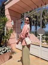 Bandolera compacta color rojo con textura de cuero, correa regulable y desmontable con diseño de rayas rojas y blancas. Cuenta con bolsillos frontales y cierre, interior forrado en tela.