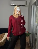 Sweater de punto color bordó con escote en V y detalle de strass aplicado en la parte frontal. Presenta mangas largas y corte holgado.