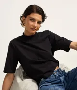 Blusa básica de algodón color celeste, con cuello alto y mangas cortas holgadas.