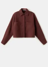 Camisa oversize color borravino, de manga larga con puños abotonados, cuello camisero, dos bolsillos de parche en el frente y cierre delantero con botones.