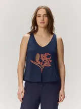 Musculosa de algodón color azul marino, con escote en V y un bordado artesanal de flor en el frente con contorno naranja y relleno dorado.